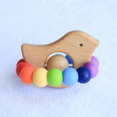 Newborn teether and Montessori toys. Handmade bird shaped teether made with BPA-free silicone and beech wood timber teething ring. Made in Australia by Bowerbird Creations. Tweet teether in bright rainbow.