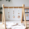 3 handmade silicone and wood baby activity gym toys in gender neutral sage hanging from a kmart wooden play gym frame