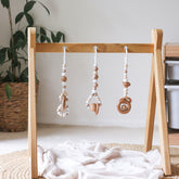 3 handmade silicone and wood baby play gym toys in beige hanging on the Kmart wooden activity gym frame