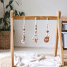 3 handmade silicone and wood baby play gym toys in beige hanging on the Kmart wooden activity gym frame
