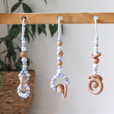 Close up of 3 handmade silicone and wood baby play gym toys in blue hanging on the Kmart wooden activity gym frame