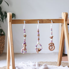 3 handmade silicone and wood baby play gym toys in floral, cream and pink hanging on the Kmart wooden activity gym frame