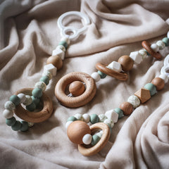 Close up of 3 handmade silicone and wood baby activity gym toys in gender neutral sage