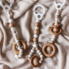 Close up of 3 handmade silicone and wood baby play gym toys in beige