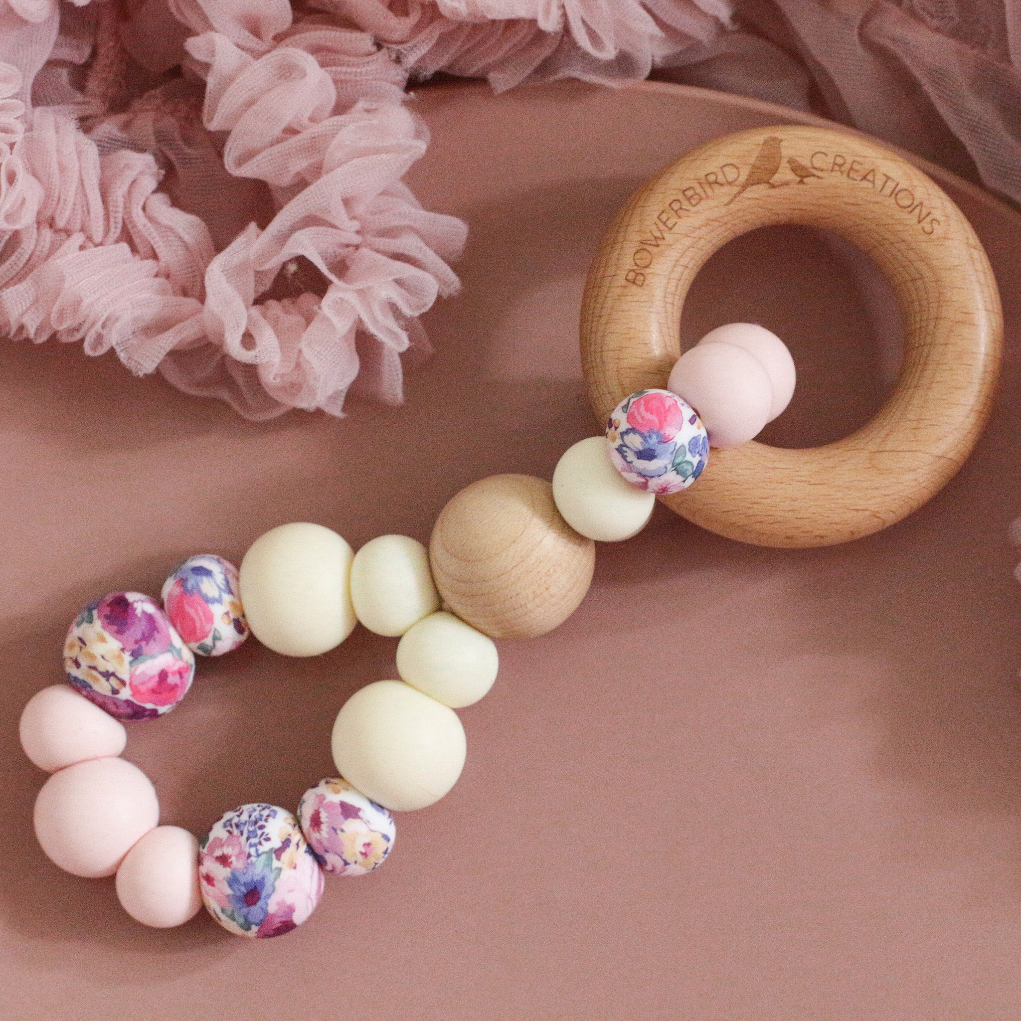 Teething toy handmade from silicone and beech wood by Bowerbird Creations. Made in Australia. Pink, cream and roses.