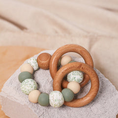 Newborn teether and montessori toys. Handmade from BPA-free silicone and beech wood timber teething rings that rattle when shaken. Sage, beige and foliage designs.