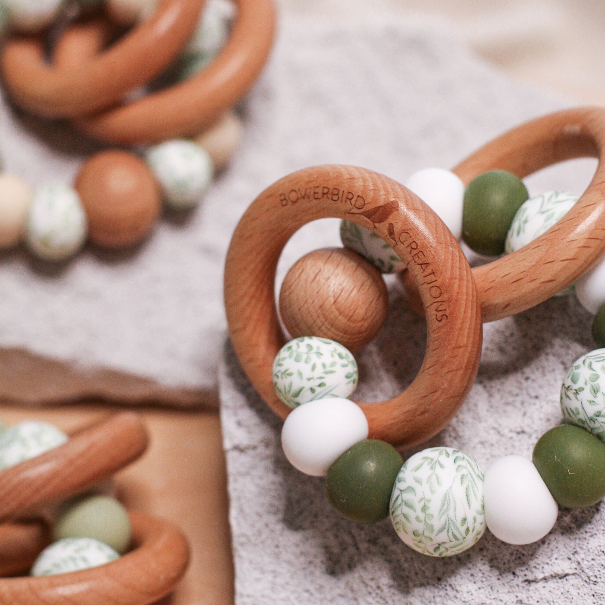 Newborn teether and montessori toys. Handmade from BPA-free silicone and beech wood timber teething rings that rattle when shaken. Olive, white and foliage designs.