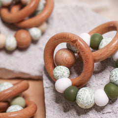Newborn teether and montessori toys. Handmade from BPA-free silicone and beech wood timber teething rings that rattle when shaken. Olive, white and foliage designs.