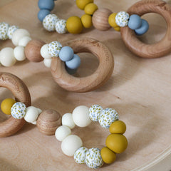 Handmade teething toys. Made in Australia from BPA-free silicone and beech wood. Non-toxic and safe. Bowerbird Creations. Blue, cream, mustard and wattle. Close up photo.