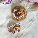Teething and Montessori toys. Handmade newborn teether with wood teething rings that rattle when shaken. Handmade in Australia from BPA-free silicone and beech wood timber. Dreamer teether by Bowerbird Creations. Pink, purple, mauve, beige and floral.