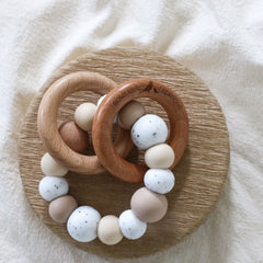 Dreamer teething ring for infants. Made with a ring of silicone beads and 2 timber teething rings that rattle when shaken. Handmade. Made in Australia. Non-toxic and safe. Beige and granite.