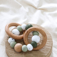 Dreamer teething ring for infants. Made with a ring of silicone beads and 2 timber teething rings that rattle when shaken. Handmade. Made in Australia. Non-toxic and safe. Green and granite.