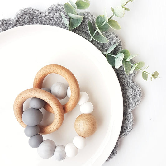 Newborn teether and montessori toys. Handmade from silicone and beech wood timber teething rings that rattle when shaken. Made in Australia. Non-toxic and safe. Grey, marble and white. 