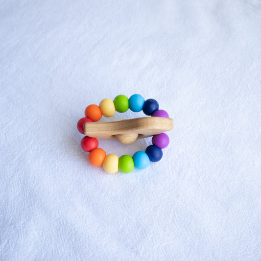 Newborn teether and Montessori toys. Handmade bird shaped teether made with BPA-free silicone and beech wood timber teething ring. Made in Australia by Bowerbird Creations. Tweet teether in bright rainbow. 