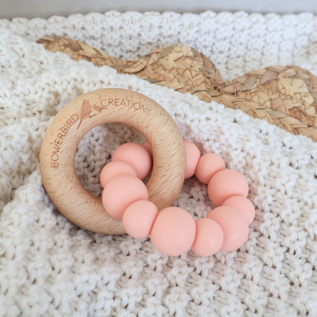 Handmade teething toy for babies, made from non-toxic silicone and beech wood. Peach. Made in Australia by Bowerbird Creations. 