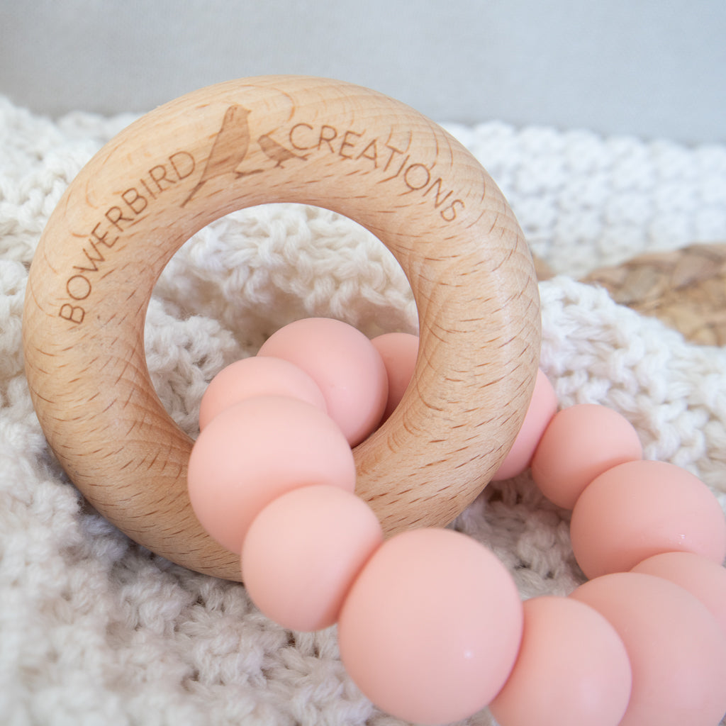 Handmade teething toy for babies, made from non-toxic silicone and beech wood. Peach. Made in Australia by Bowerbird Creations. 