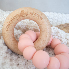 Handmade teething toy for babies, made from non-toxic silicone and beech wood. Peach. Made in Australia by Bowerbird Creations. 