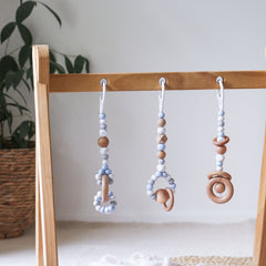 Close up of 3 handmade silicone and wood baby play gym toys in blue and white hanging on the Kmart wooden activity gym frame
