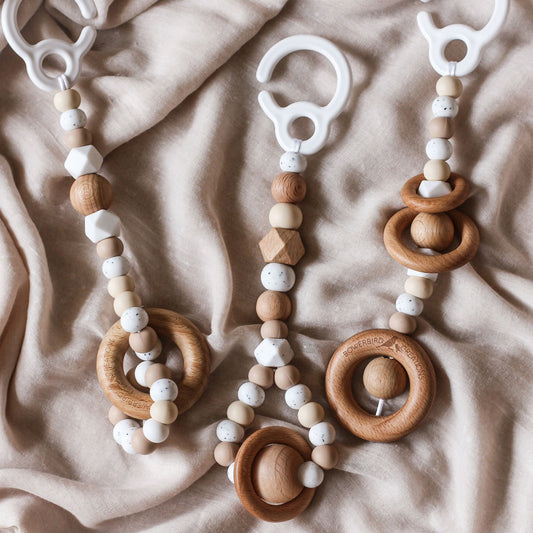 Close up of 3 handmade silicone and wood baby play gym toys in beige