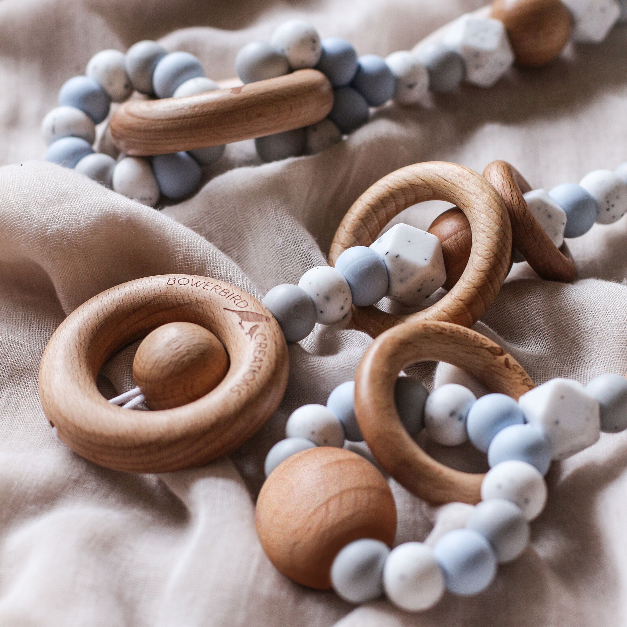 Close up of 3 handmade silicone and wood baby play gym toys in blue and white