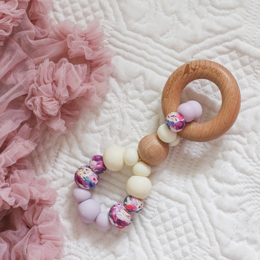 Teething toy handmade from silicone and beech wood. Made in Australia by Bowerbird Creations. Infinity teether toy in lilac, cream and roses. 