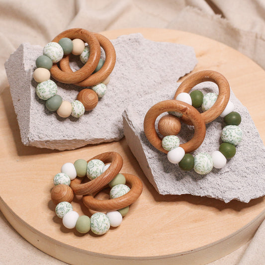 Newborn teether and montessori toys. Handmade from BPA-free silicone and beech wood timber teething rings that rattle when shaken. Sage, lint, olive, white, beige and foliage designs. 
