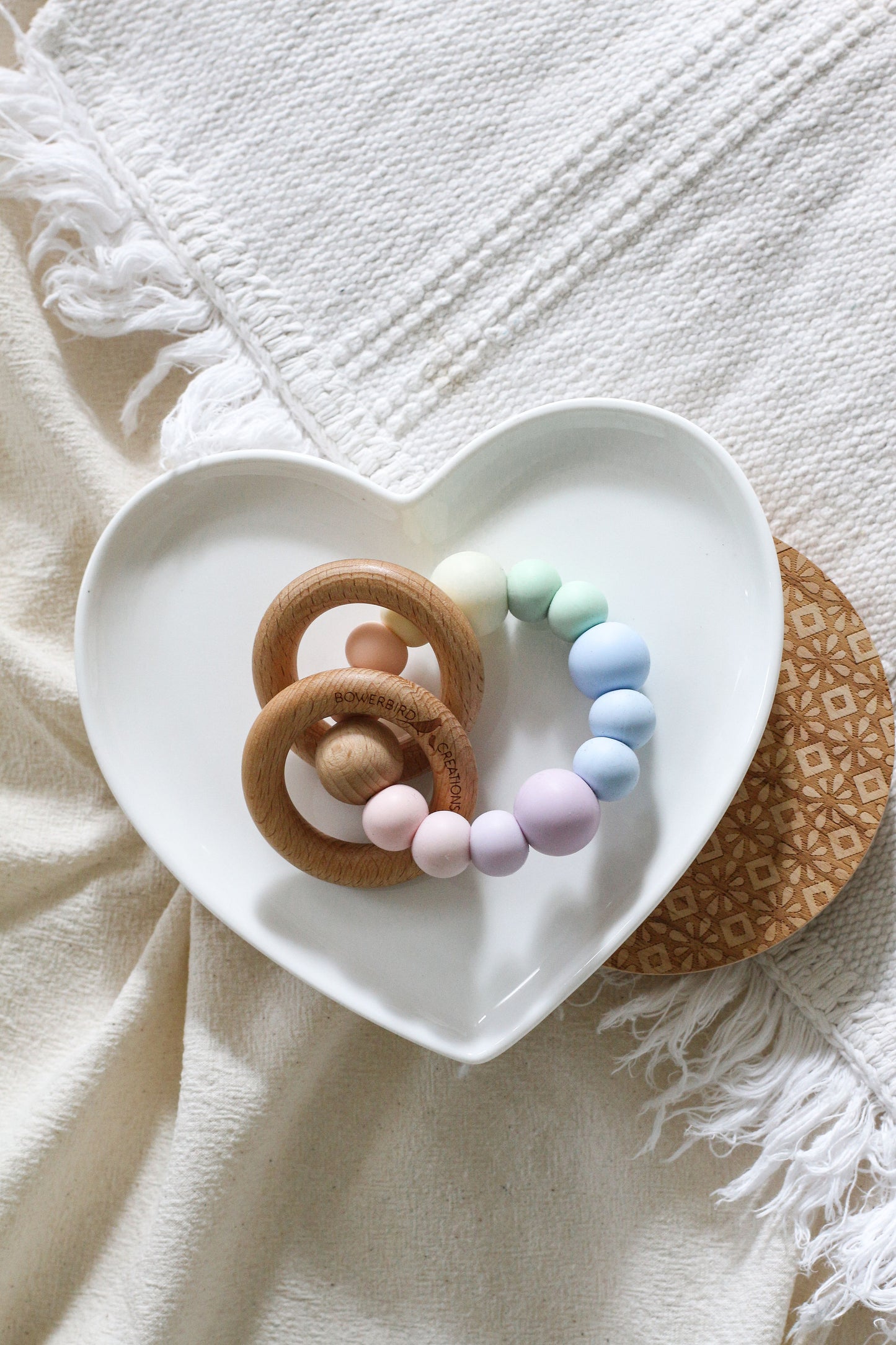 Teether/sensory toy featuring 2 wooden rings that rattle. Handmade from silicone and natural wood. Pastel and muted rainbow. Pastel rainbow.
