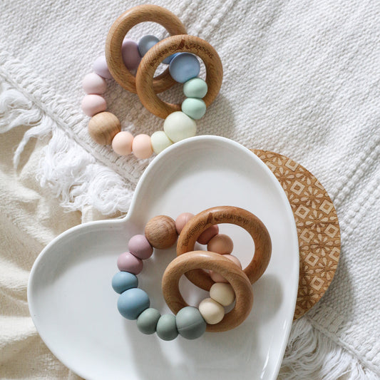 Newborn teether and montessori toys. Handmade with BPA-free silicone and natural beech wood timber teething rings. Dreamer teething toy by Bowerbird Creations. Made in Australia. Muted and pastel rainbow. 