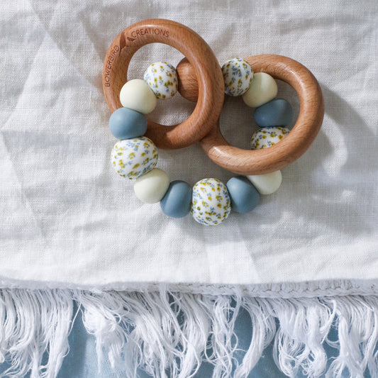 Handmade teething toys made in Australia from silicone beads and beech wood timber teething rings that rattle when shaken. Dreamer Teether by Bowerbird Creations. Blue, cream and Wattle. 