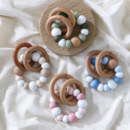 Dreamer teething ring for infants. Made with a ring of silicone beads and 2 timber teething rings that rattle when shaken. Handmade. Made in Australia. Non-toxic and safe. Blue, green, pink, beige and granite. 
