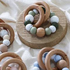 Dreamer teething ring for infants. Made with a ring of silicone beads and 2 timber teething rings that rattle when shaken. Handmade. Made in Australia. Non-toxic and safe. Blue, green, pink, beige and granite. 