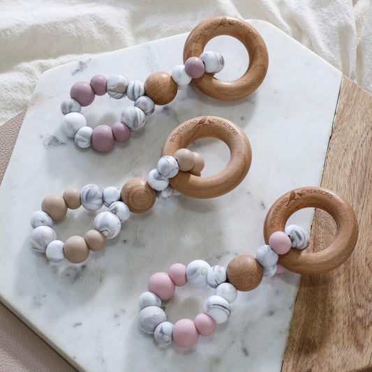 Handmade teething toys in beige, pink, mauve and marble. Made in Australia by Bowerbird Creations from BPA-free silicone and beech wood. 