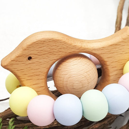 Newborn teether and Montessori toys. Handmade bird shaped teether made with BPA-free silicone and beech wood timber teething ring. Made in Australia by Bowerbird Creations. Tweet teether in pastel rainbow. 