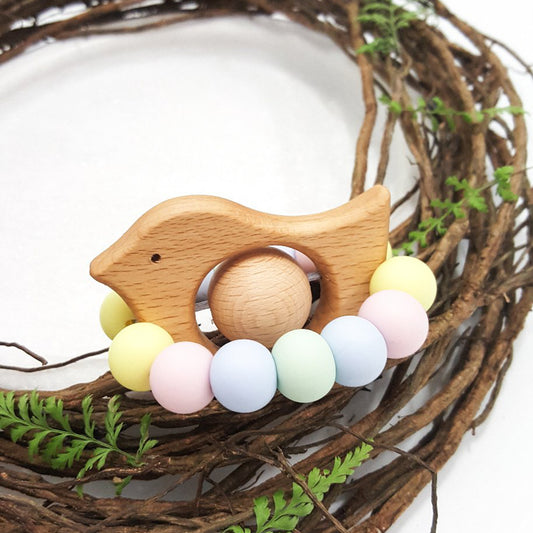 Newborn teether and Montessori toys. Handmade bird shaped teether made with BPA-free silicone and beech wood timber teething ring. Made in Australia by Bowerbird Creations. Tweet teether in pastel rainbow. 