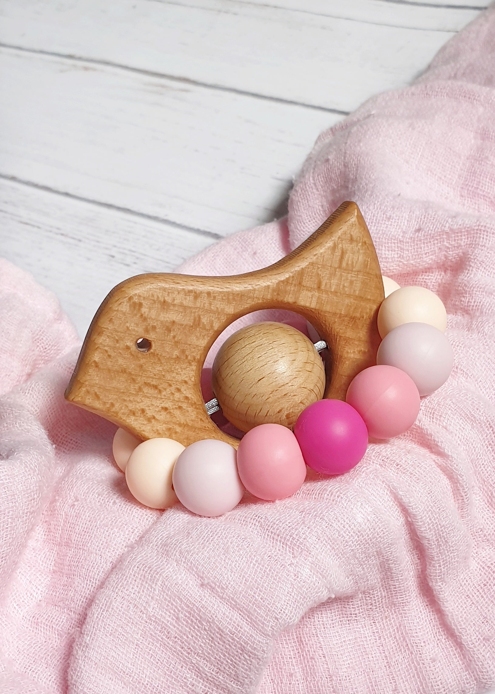 Bird shaped teething/sensory toy for babies. Pink, handmade from silicone and natural beech wood.